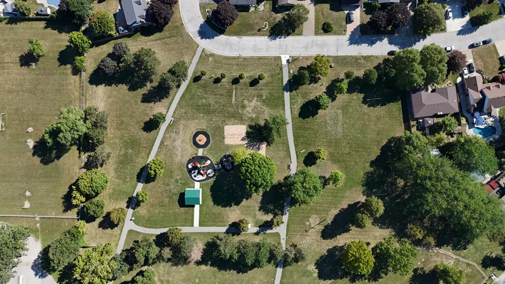 Aerial view of park showing playground, pavilion, disc golf course, pathway, open green space and trees