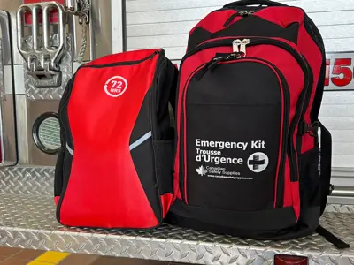 Two red emergency kit bags sitting on the back of a fire engine