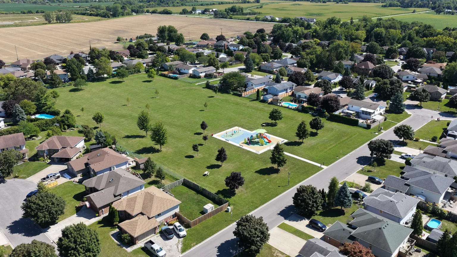 Aerial view of park showing pathway leading to playground, open grassed area and trees.