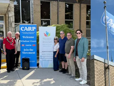 Members of Council, Amherstburg staff and the public pose in front of Town Hall to acknowledge Seniors Month in Ontario. The Canadian Association of Retired Persons flag flies above Town Hall
