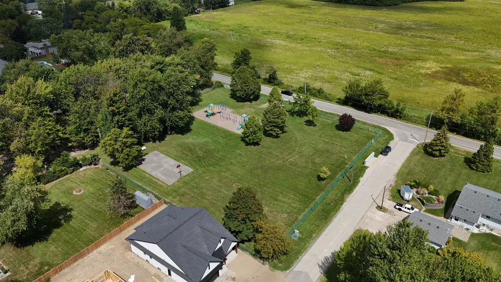 Aerial view of park showing playground, basketball court, open grassed areas and trees