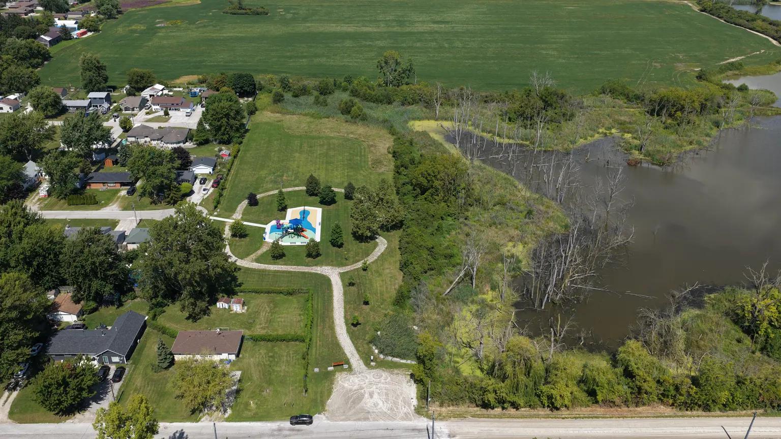 Aerial image of park showing playground, trails, parking lot, green space and trees.