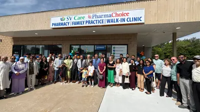 A large group of people stand for a photo below a sign for a new medical facility in Amherstburg. SV Care Medical & Walk-in-Clinic