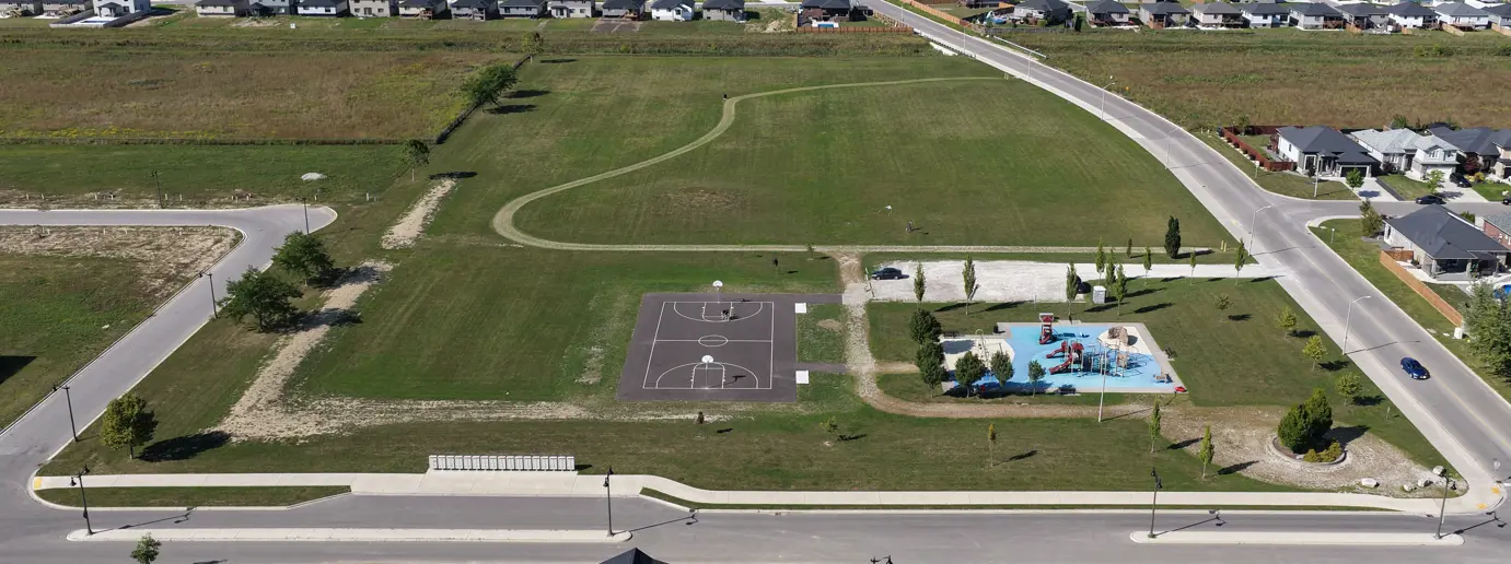 Arial image of park showing playground, sports court, trail, greenspace and trees.