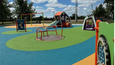 Soft ground and play structures with swings in the background