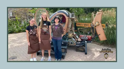 Three female volunteers stand in front of a time machine photo display at Amherstburg Uncommon Festival