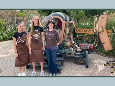 Three female volunteers stand in front of a time machine photo display at Amherstburg Uncommon Festival